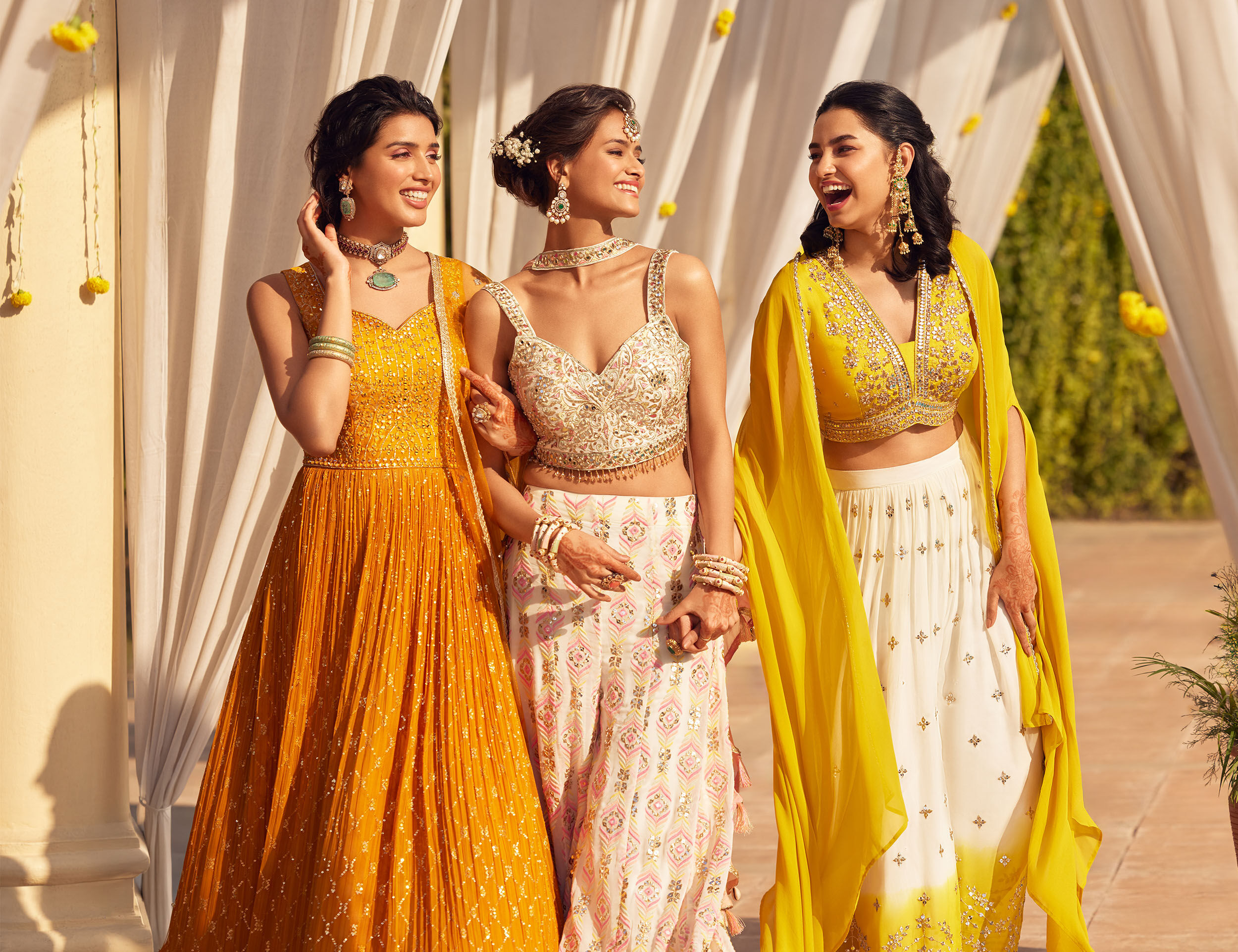 Women flaunting elegant white and yellow lehengas for wedding.